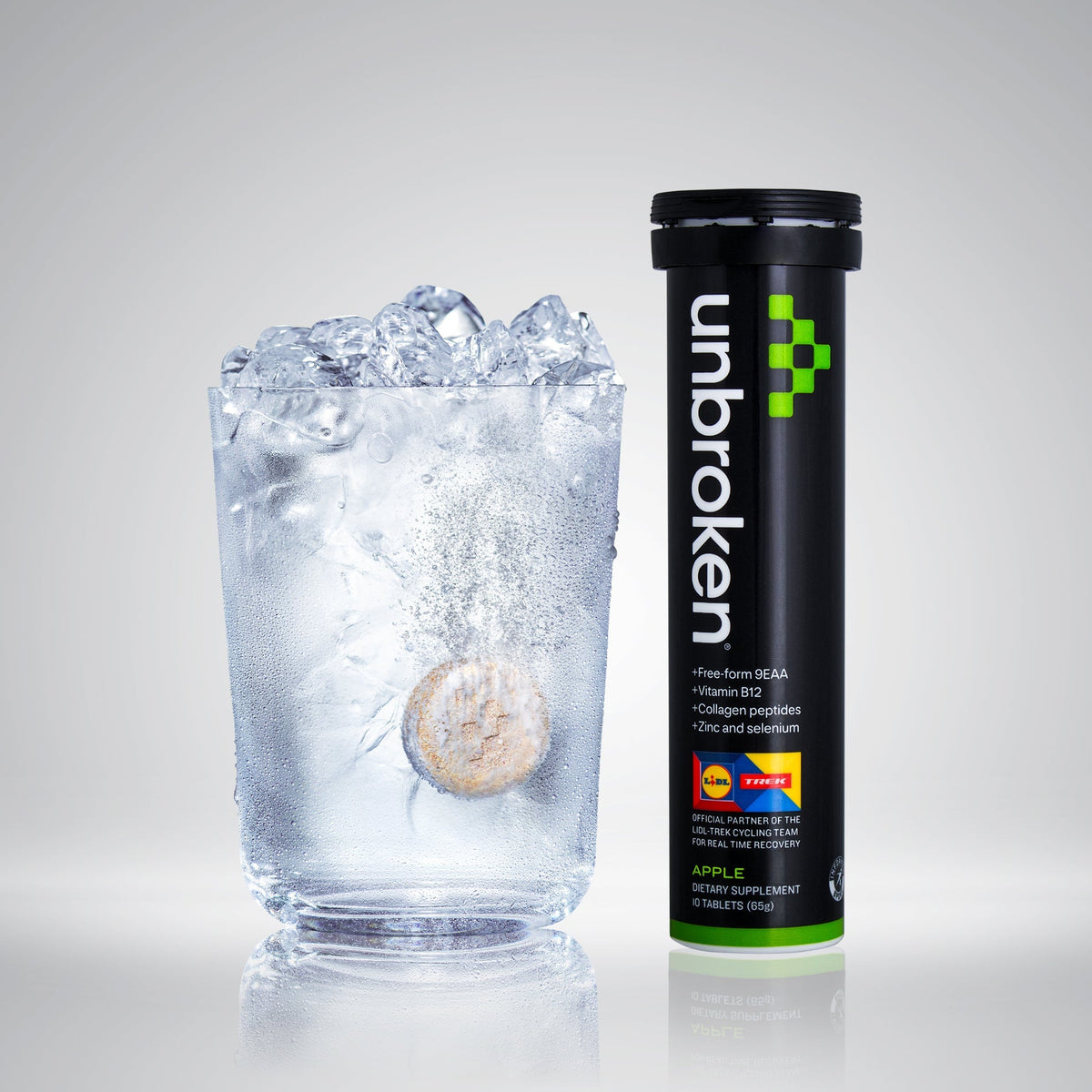 Unbroken Apple tube next to a glass of iced water with a tablet dissolving
